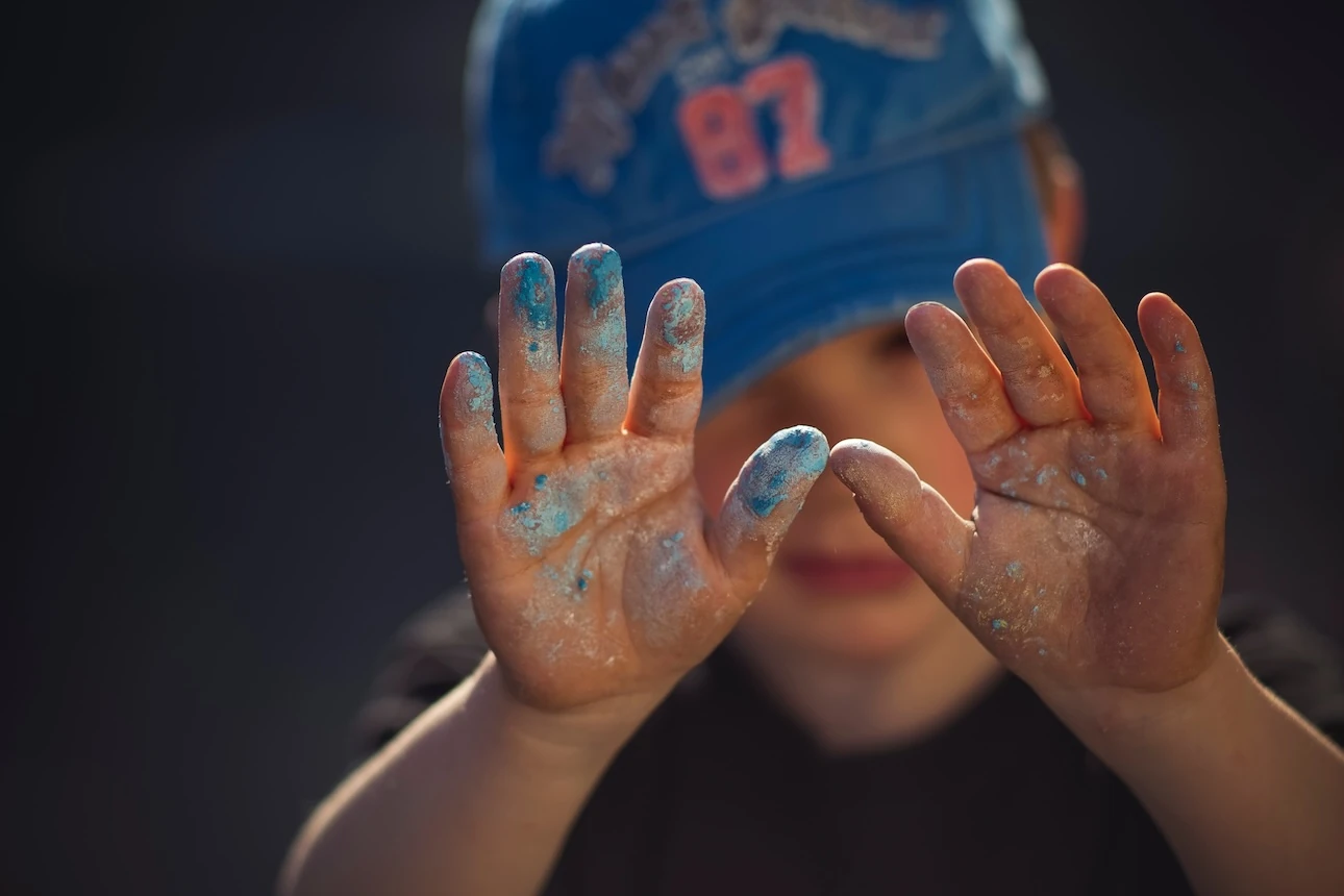 Junge zeigt seine farbbeschmierten Hände